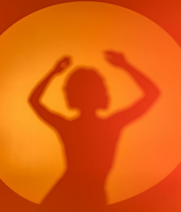 Woman performing a light, energetic movement in a bright room.